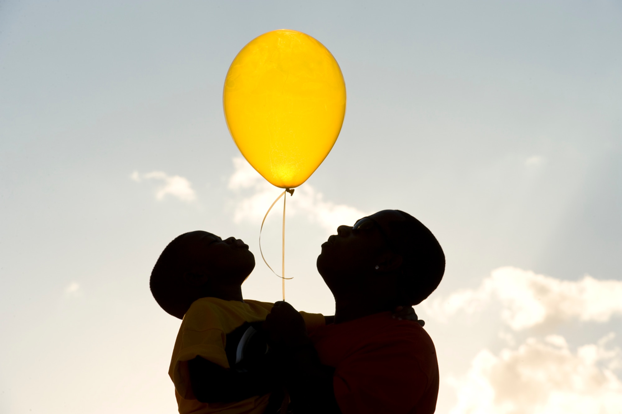 On his mom?s birthday Nov. 11, Nathaniel and his uncle  (Staff Sgt. Aron Lee) get ready to send one of the 12 yellow balloons they release every year to heaven. Lee says his nephew enjoys this celebration, which makes him feel closer to his mom. 
(Photo by TSgt Samuel Bendet)