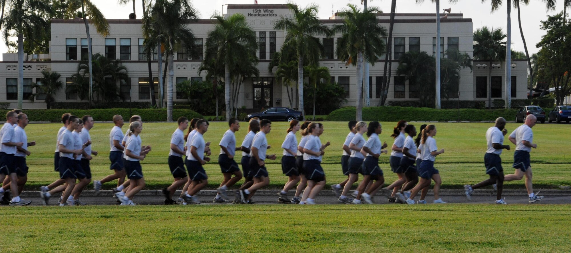 Airmen from the 15th Wing at Joint Base Pearl Harbor-Hickam, Hawaii, run by the 15th WG headquarters building during the monthly "Warrior Run" Apr. 1. The run, which spans approximately two miles, was hosted this month by the 15th Medical Group. (U.S. Air Force photo by Staff Sgt. Nathan Allen)
