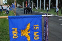 The guidon from the 15th Medical Group is held at attention for the approach of the American Flag before the monthly "Warrior Run" Apr. 1 which begins and ends at Hickam Mall. The run, which spans approximately two miles, was hosted this month by the 15th MDG. (U.S. Air Force photo by Staff Sgt. Nathan Allen)