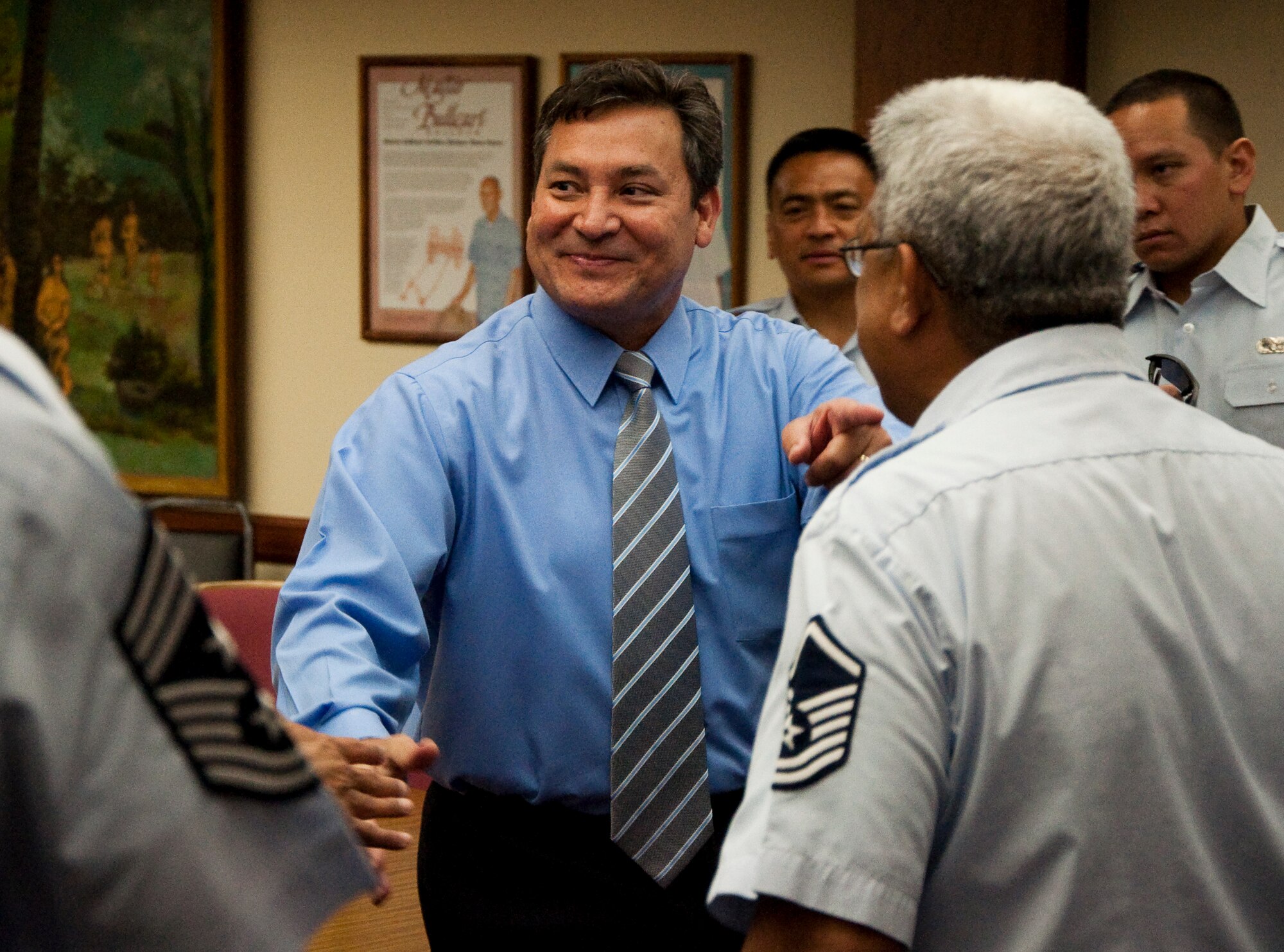 Gov. Edward B. Calvo, Guam governor shakes hands with Maj. Anthony C. San Nicolas, 44th Aerial Port Squadron commander as he points to his former classmate, Master Sgt. Ramon Peredo, 44th APS Knowledge Operations Manager and lead Client Support Administrator, after signing a proclamation designating March as Month of the Air Force Reserve on Guam. The proclamation was signed on the 30th anniversary of the arrival of Air Force Reserve on Guam. U.S. Air Force Photo/Staff Sgt. Erin Smith