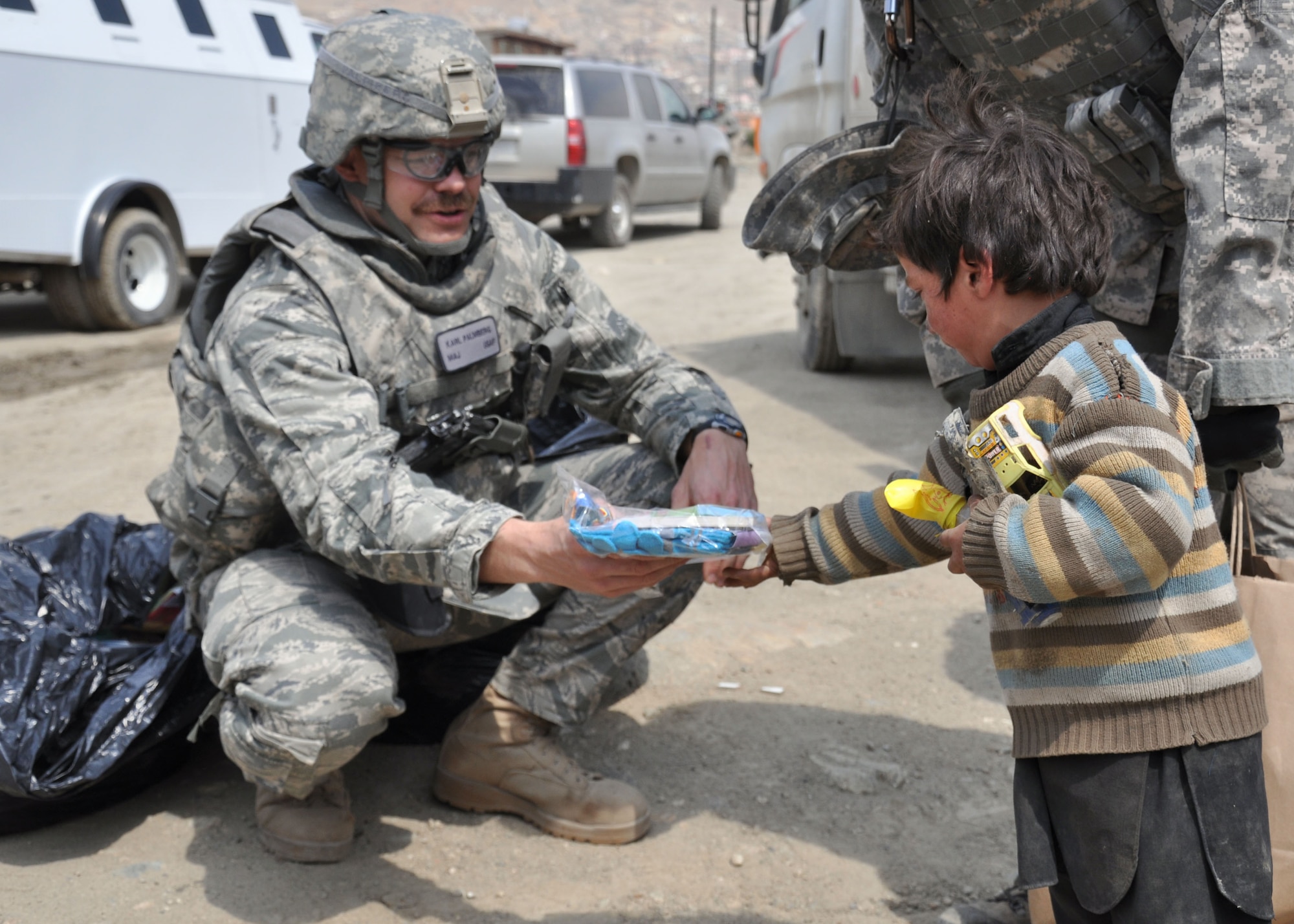 Air Force Maj. Karl Palmberg gives a bag of toys to an Afghan child during a volunteer community relations supply donation to a refugee camp in Kabul March 31, 2011.  Palmberg is a personnelist in NATO Training Mission-Afghanistan who is deployed from Luke Air Force Base, Ariz.  (U.S. Air Force photo/Tech. Sgt. April Lapetoda)