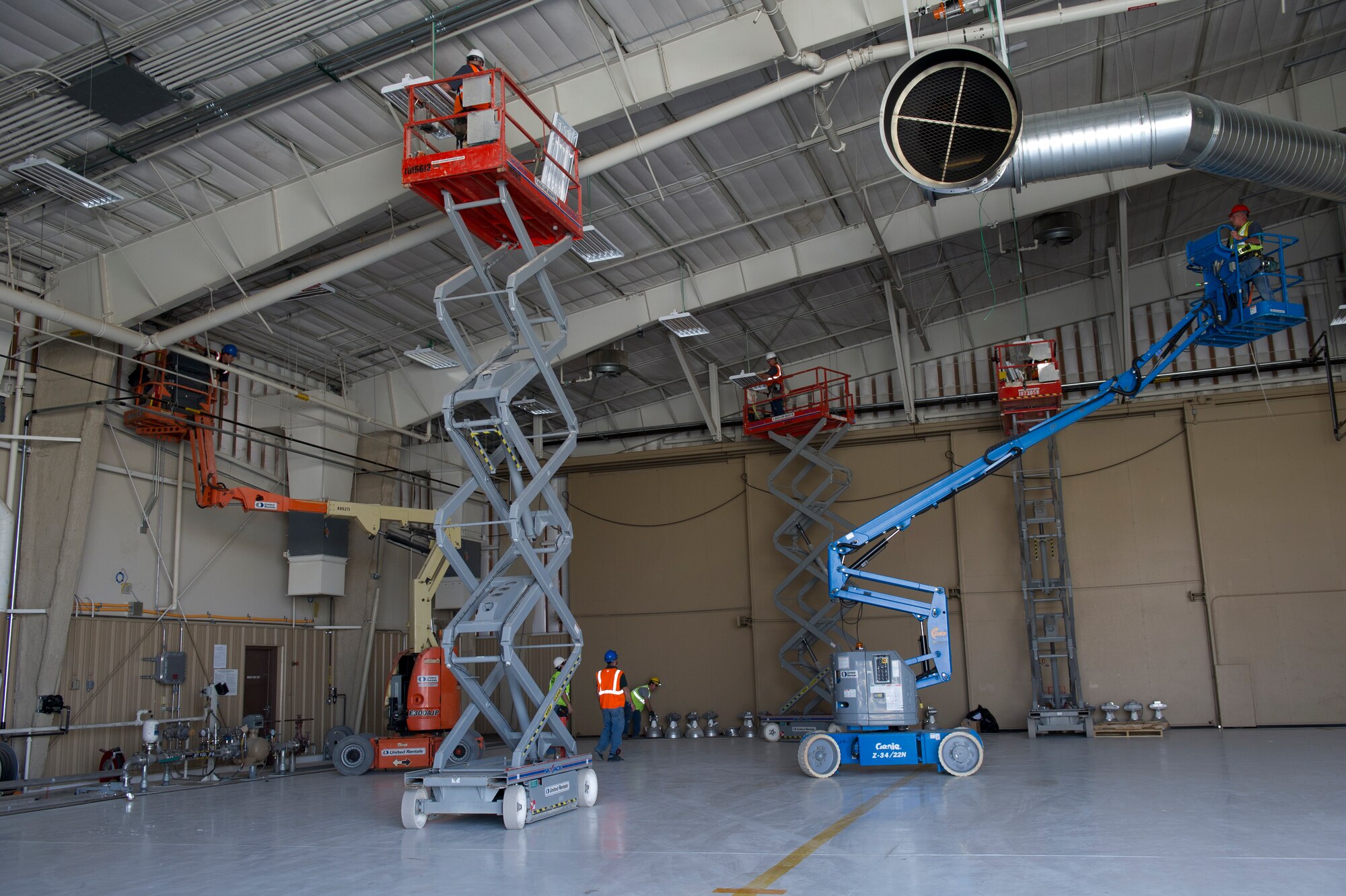 HOLLOMAN AIR FORCE BASE, N.M. -- Contractors work with the 49th Civil Engineer Squadron Assets Management office to install energy efficient lighting in an aircraft hangar March 24, 2011. The high output fluorescent lighting is network controlled, and is predicted to save 40 percent of energy compared to the old lighting. (U.S. Air Force photo by Airman 1st Class Eileen Payne/Released)