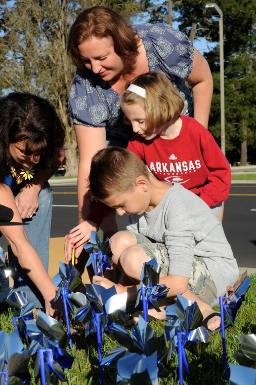 VANDENBERG AIR FORCE BASE, Calif. – In support of Child Abuse Awareness Month, Maddy Stanger along with his sister, Greenlee, and their mother, Judi, places a pinwheel into the ground for the Pinwheels for Prevention garden display at the main gate here Friday, April 1, 2011. Five hundred and seventy-six pinwheels were placed to visually remind people of the very real threat and need for child abuse prevention. (U.S. Air Force photo/Senior Airman Lael Huss)