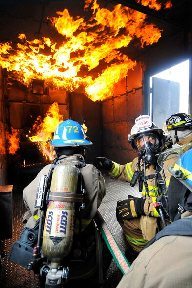 AEDC Fire Department Assistant Chief for Operations George DeShields directs some of the base’s mutual aid partner firefighters from Murfreesboro and Manchester as they fight a simulated heater fire with “rollover” onto the ceiling in the mobile trainer from the Alabama Fire College. The trainer was on base March 25-27 so all three shifts of the AEDC fire department could experience the live fire training. About 40 firefighters from other area fire departments also participated. (Photo by Rick Goodfriend)