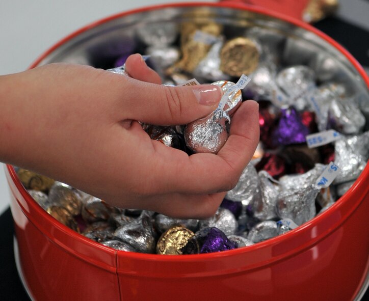 Staff Sgt. Faith Sturm, 2nd Medical Support Squadron, grabs a hand full of chocolate to hand out at the kissing booth in the base exchange on Barksdale Air Force Base, La., March 31. The booth was set-up to promote a "can I kiss you" culture and upcoming events for Sexual Assault Awareness Month. (U.S. Air Force photo/Airman 1st Class Micaiah Anthony)(RELEASED) 