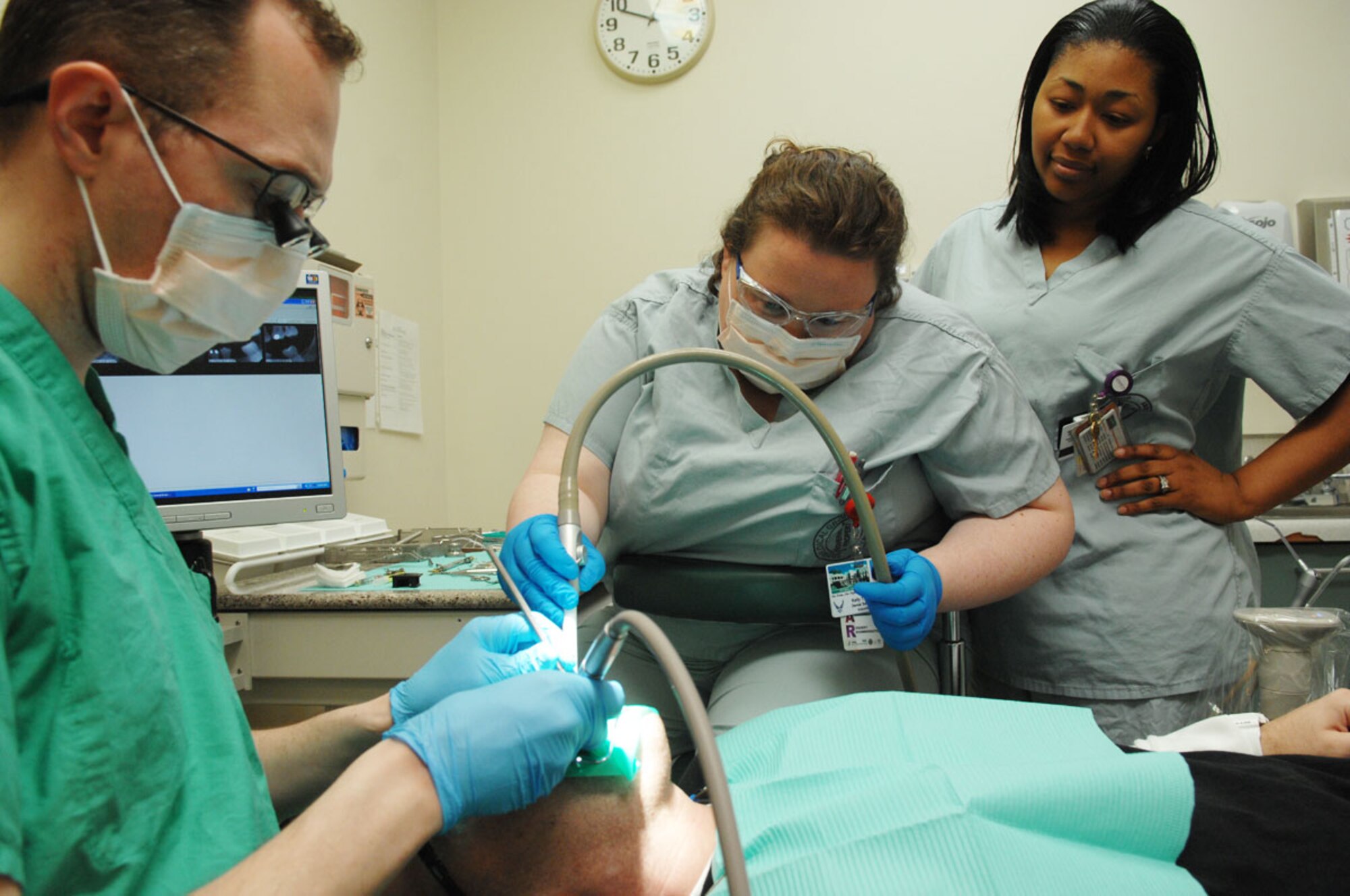 Kelly Thomas, middle, a student in the American Red Cross Dental Assisting Program,
assists (Dr.) Air Force Capt. Anthony Mecham, 673d Dental Squadron, with a procedure at the clinic as Stephanie Savant, a veteran student of the dental assisting program, looks on., March 28. (U.S. Air Force photo/Staff Sgt. Jeremy Larlee)