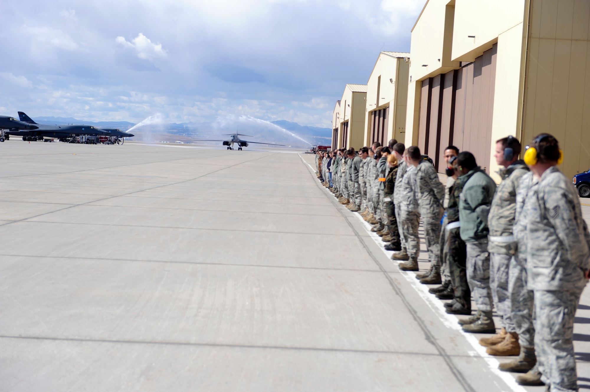 Airmen from the 28th Bomb Wing await the arrival of a B-1 Lancer as the 28th Civil Engineer Squadron fire department pays tribute to their return at Ellsworth Air Force Base, S.D., March 30, 2011. During Operation Odyssey Dawn, coalition forces struck targets that posed a direct threat either to the civilian population or to partner nation aircraft enforcing a United Nations established no-fly zone. ((U.S. Air Force photo/Senior Airman Adam Grant)