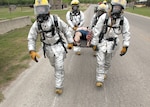 Firefighters from the 802nd Civil Engineer Squadron carry a patient to safety after a simulated chemical attack during an anti-terrorism exercise at Lackland March 30. The three-day exercise simulated the release of a nerve agent and involved units at Lackland, Randolph AFB and Fort Sam Houston. (U.S. Air Force Photo/Robbin Cresswell)