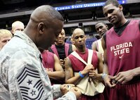 Chief Master Sgt. Juan Lewis, 502nd Air Base Wing command chief, exchanges coins with Florida State's Bernard James during a practice for a Southwest regional semifinal in the NCAA college basketball tournament March 24. Mr. James served in the Air Force from 2003 - 2008, spending time at Lackland for basic military training, security forces training and leadership schools. (U.S. Air Force photo/Tony Morano) 