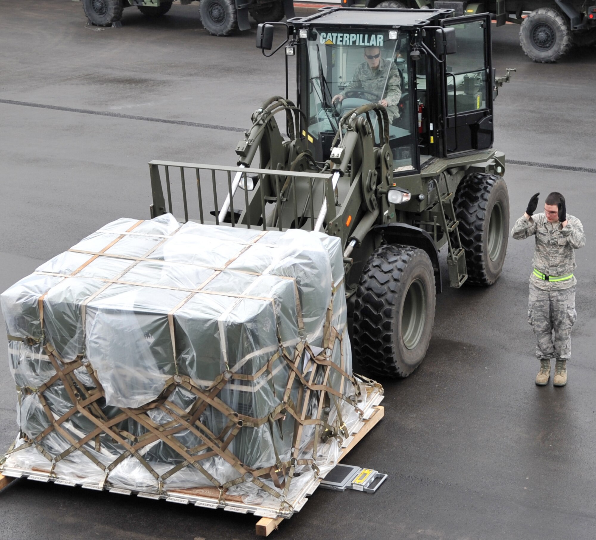 U.S. Air Force Senior Airman Justin Burger, 86th Logistics Readiness Squadron combat readiness technician, directs Airman 1st Class Philip Smouse, 86th LRS air transport, as he moves cargo during an in-check in support of Operation Unified Protector, Ramstein Air Base, Germany, April 1, 2011. Unified Protector is a NATO-led operation in Libya to protect civilians and civilian-populated areas under threat of attack. (U.S. Air Force photo by Senior Airman Caleb Pierce)
