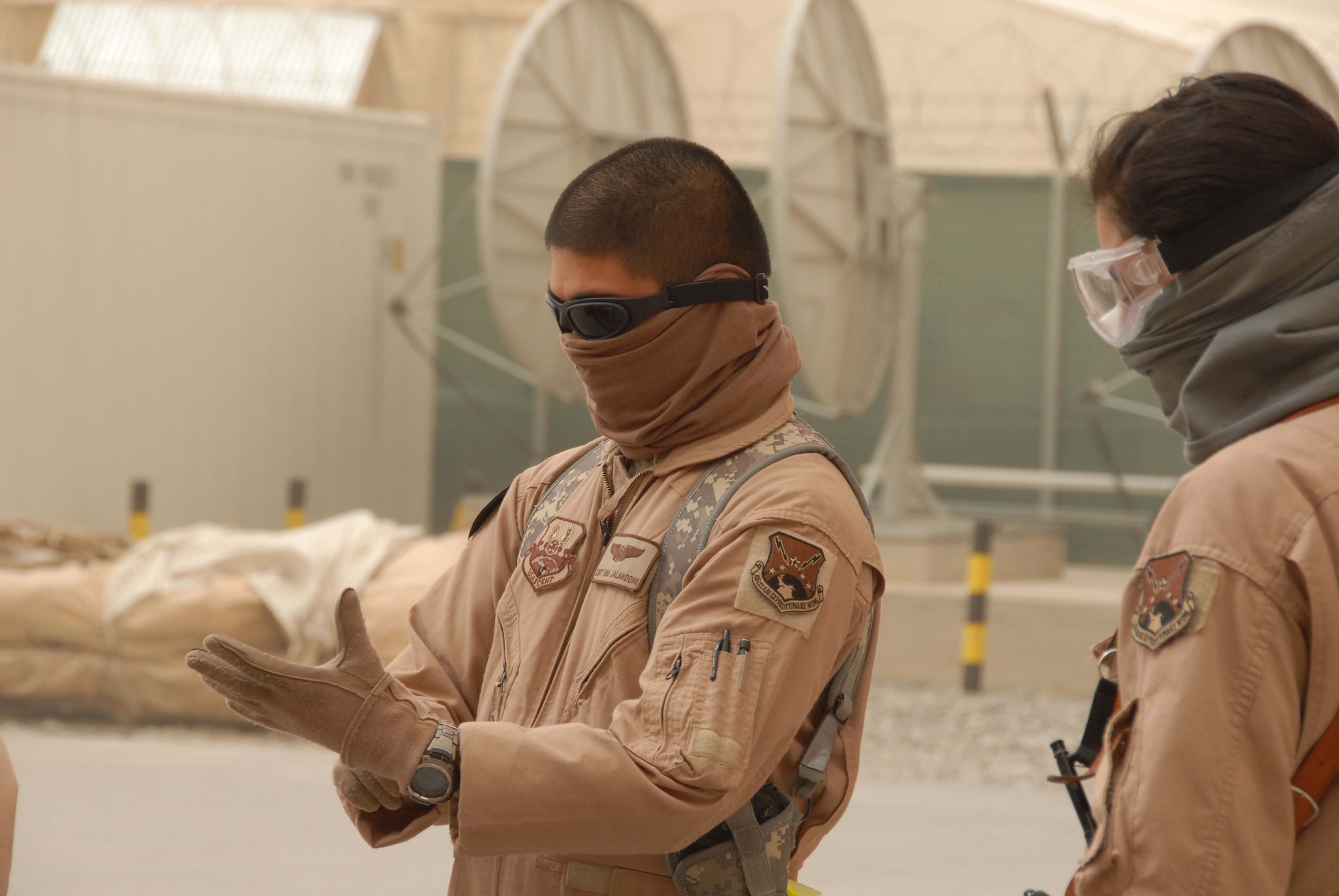 Staff Sgt. Sean Jaladoni and Technical Sgt. Denise Bravo, medics with the 451st EAES, prepare to move patients at Kandahar Airfield March 27th. The medics work with volunteers to load patients on a bus that will carry them to a C-130 and fly them out of Kandahar. Due to a dust storm on March 27th, the medics and volunteers wore goggles and scarves in addition to gloves to avoid the sand and dirt.