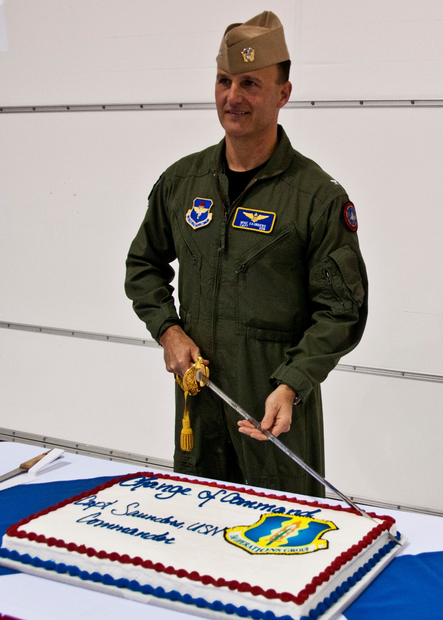 Navy Capt. Michael Saunders prepares to slice the celebration cake after taking command of the 33rd Operations Group March 31.  Shortly before he partook in his service’s tradition, he witnessed an Air Force tradition for the first time - Captain Saunders name was placed on the cockpit  side of an F-16 by a maintainer from Luke AFB, Ariz.  The Navy officer was the first senior leader to arrive at the wing when it transitioned in 2009 from an operational F-15 combat unit to DoD’s Joint Strike Fighter training wing. As the former 33rd OG vice commander, Capt. Saunders stepped up to replace Air Force Col. Jim Ravella in leading the group that is solely responsible for creating the first F-35 pilot training program.  (U.S. Air Force photo/Chrissy Cuttita)