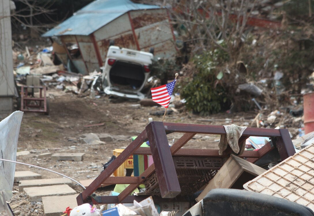 An American flag is placed on a pile of debris which used to be the home of a local resident here.  The residents of the area placed the flag as a sign of thanks to the U.S. Marines, who are participating in Operation Field Day, a clearing and cleanup project designed to open harbor access and area roads on the isolated island.  As Marines cleared the area, they took time to locate personal items which could be salvaged by the local residents.  The 31st MEU is participating in Operation Tomodachi at the request of the Japanese government after the 9.0 earthquake and tsunami devastated the northeast coast of Japan.