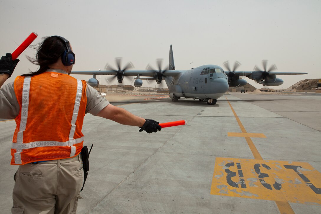 An Ali Al Salem Air Base flightline worker directs a KC-130J Hercules with Marine Aerial Refueler Transport Squadron 252, to its refueling location as it taxis, April 3. The aircraft stopped in Kuwait to refuel during a 15-hour flight from Camp Bastion, Afghanistan to Naval Support Activity Souda Bay, Greece while escorting three MV-22B Ospreys with Marine Medium Tiltrotor Squadron 266 to the USS Kearsarge, 26th Marine Expeditionary Unit, after a deployment in support of operations in Afghanistan.