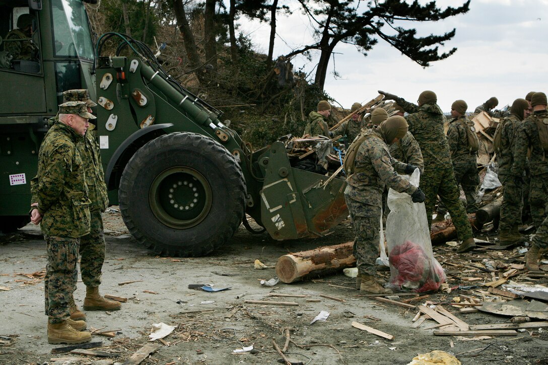 Lt. Gen. Kenneth J. Glueck, III Marine Expeditionary Force commanding general and Task Force 505 commander, watches Marines and sailors pick up debris during a clean-up operation here April 3. The 31st Marine Expeditionary Unit, III MEF, is aiding local government authorities and personnel in the clean up after an earthquake and tsunami struck the island March 11.