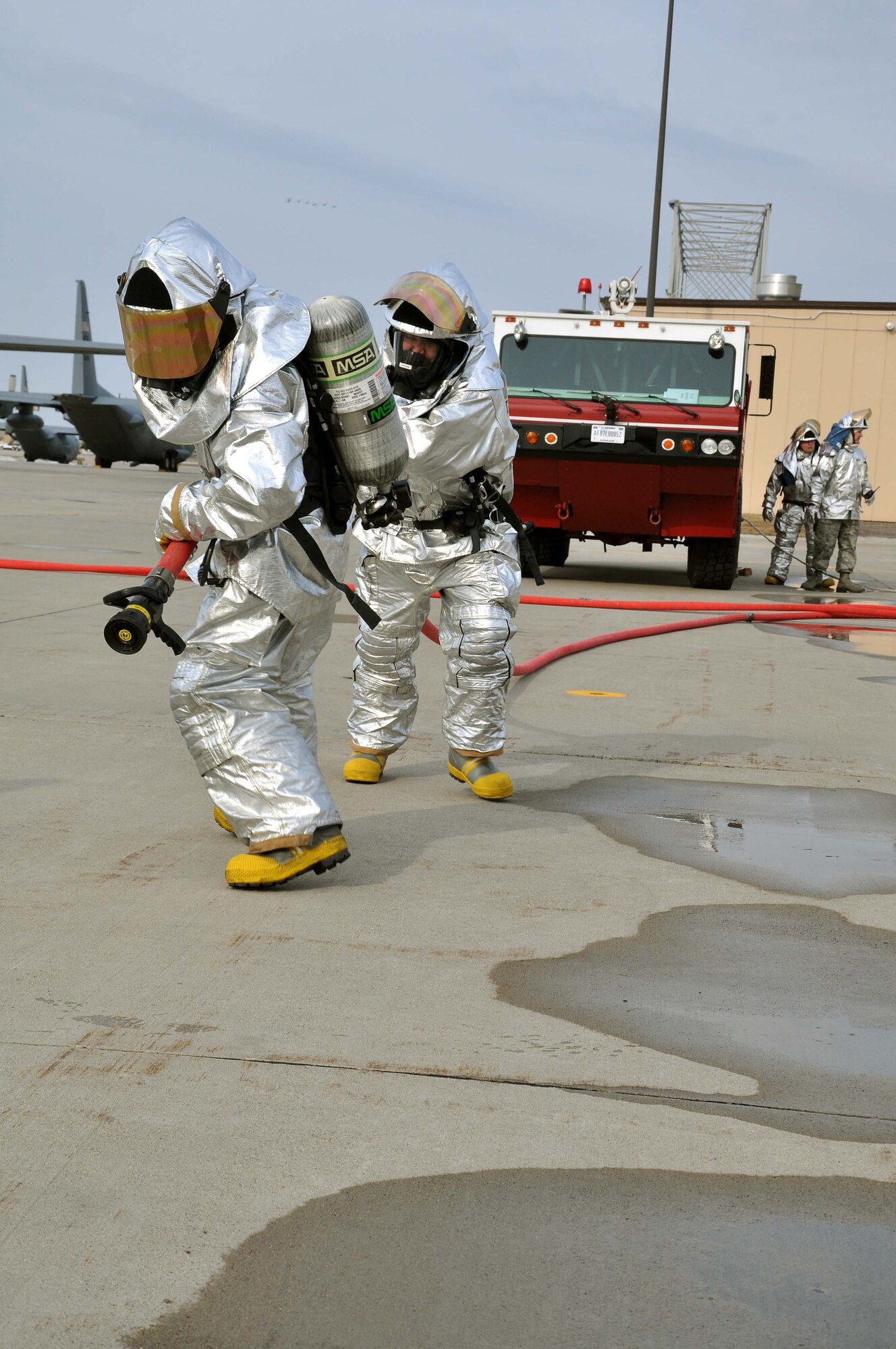 Firefighters from the 934th Airlift Wing, drag fire hose during a simulated C-130 Hercules fire April 3 2011. (Air Force Photo/TSgt Bob Sommer)
