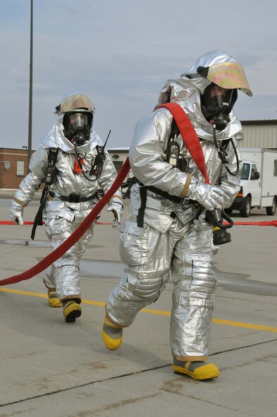 Firefighters from the 934th Airlift Wing, drag fire hose during a simulated C-130 Hercules fire April 3 2011. (Air Force Photo/TSgt Bob Sommer)