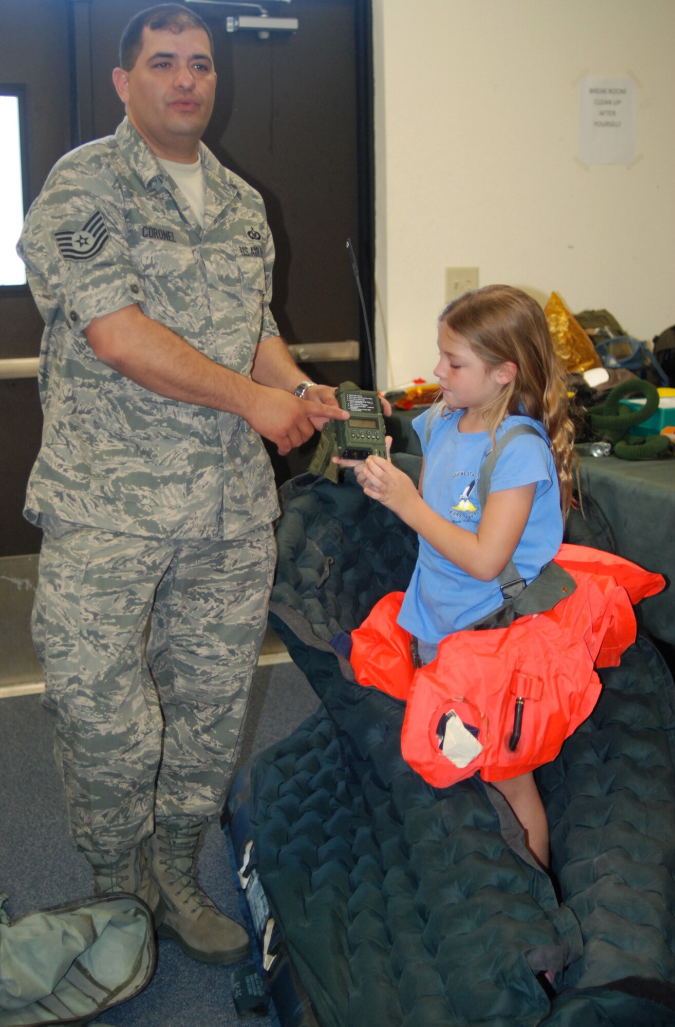 PATRICK AIR FORCE BASE, Fla. -- Air Foce Reservist Technical Sgt. Xavier Coronel, aircrew life support technician, demonstrates how the equpiment used by pararescuemen here work, with the help of Emma Binder, a young Adventure Maiden. Sergeant Coronel was one of many Reservists who volunteered to demonstrate how pararescuemen are capable of doing their jobs successfully. This was one of a few demostrations the men and women with Adventure Maidens were able to witness on their tour of the 920th Rescue Wing here. (U.S. Air Force photo/Airman First Class Natasha Dowridge)