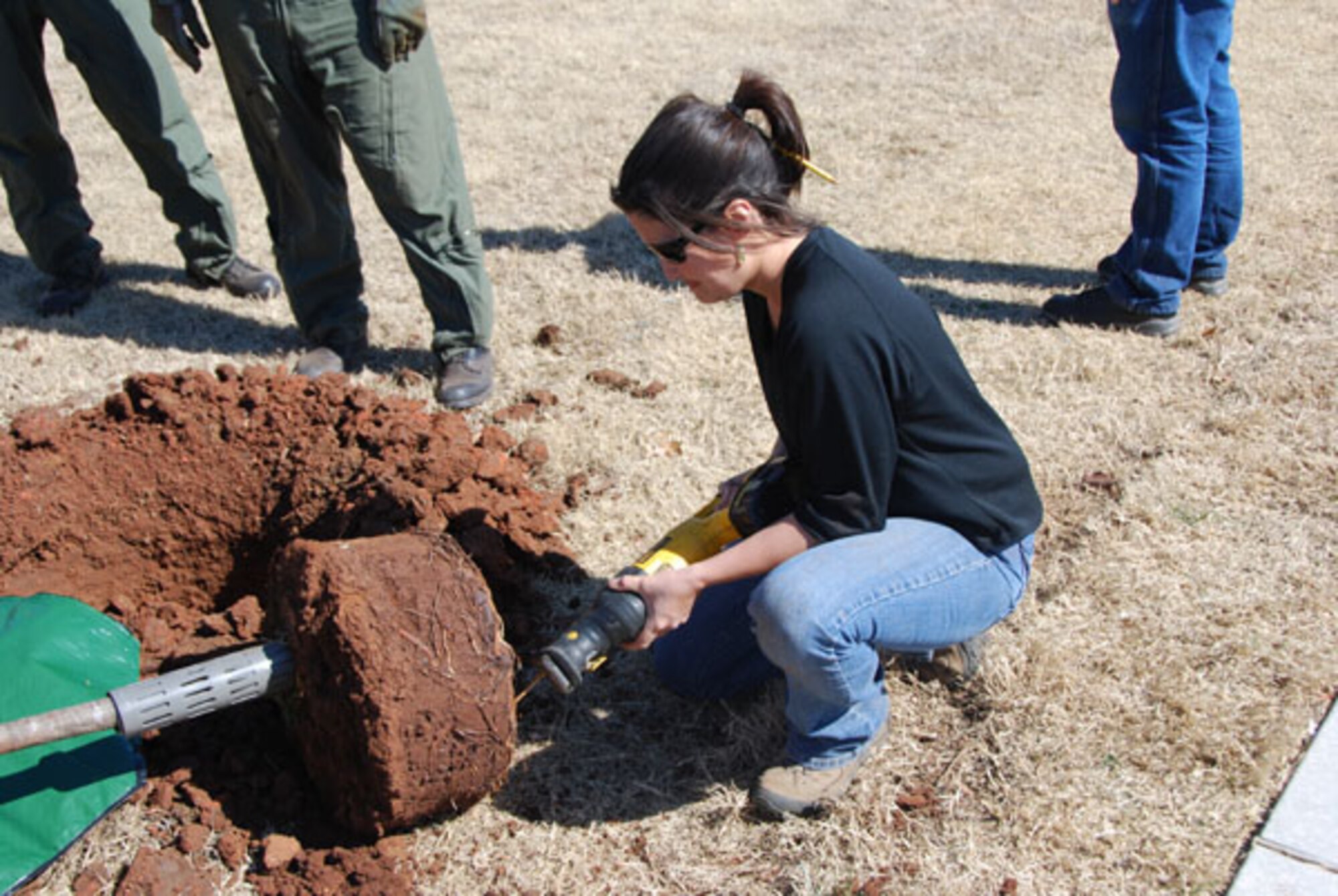 Donna Nolan, a co-supervisor for the project, uses a reciprocating saw to trim roots off a tree about to be planted. The tree planting project involved 59 trees, more than 25 volunteers, two hours and one sunny afternoon to beautify the exterior of the Reserve-Guard operations building on the reserve camputs of Tinker Air Force Base on March 10, 2011.