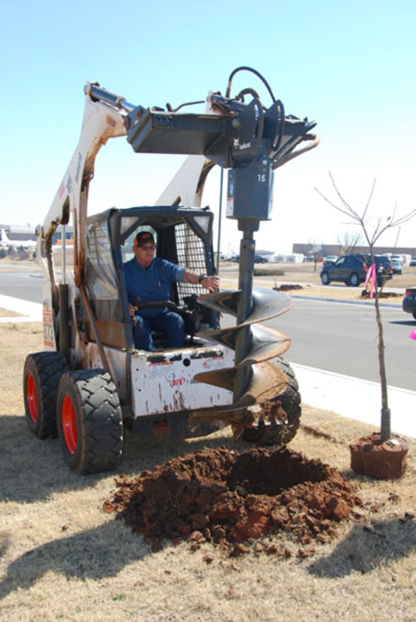 A heavy equipment operator drills a hole for a tree to be planted. The tree planting project involved 59 trees, more than 25 volunteers, two hours and one sunny afternoon to beautify the exterior of the Reserve-Guard operations building on the reserve camputs of Tinker Air Force Base on March 10, 2011.