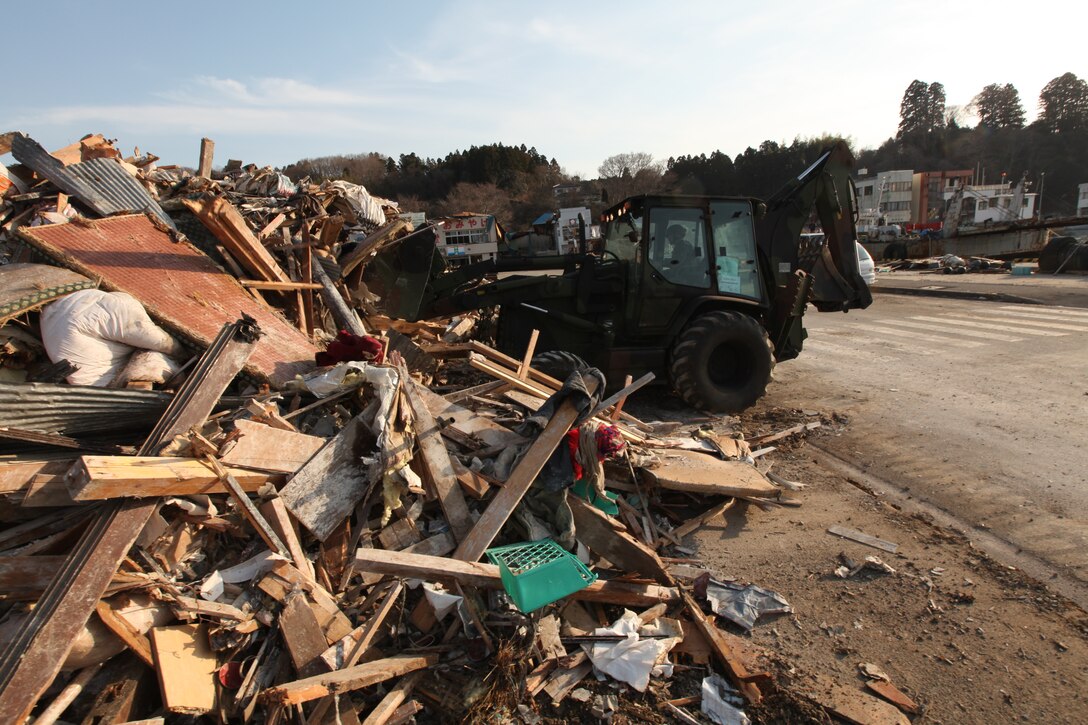 A Marine driving a backhoe with the 31st Marine Expeditionary Unit, pushes rubble and debris to the side of the road during a humanitarian assistance/disaster relief mission at Uranohama Port, April 1. The mission was in support of Operation Tomodachi.  The 31st MEU's involvement is part of a larger U.S. government response, after a 9.0 earthquake and subsequent tsunami struck Japan causing widespread damage.  The 31st MEU is ready to support our Japanese partners and to provide assistance when called upon.