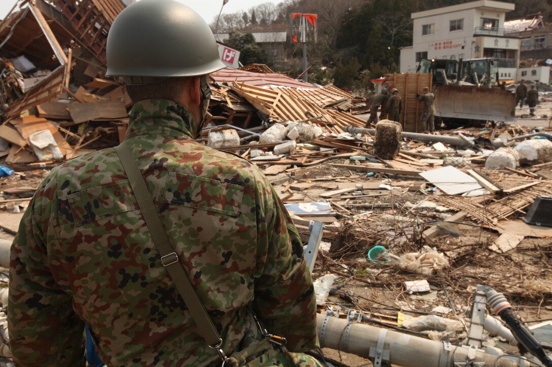 Japan Self Defense Force Maj. Hiroshi Sakuma observes as Marines with Battalion Landing Team 2nd Battalion, 5th Marines, 31st Marine Expeditionary Unit, handle part of a wall from a destroyed house during a humanitarian assistance/disaster relief mission at Uranohama Port, April 2. The mission was in support of Operation Tomodachi.  The 31st MEU's involvement is part of a larger U.S. government response, after a 9.0 earthquake and subsequent tsunami struck Japan causing widespread damage.  The 31st MEU is ready to support our Japanese partners and to provide assistance when called upon.