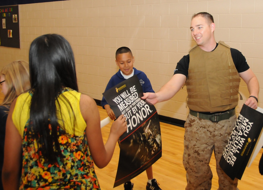 CHANDLER, Ariz. - Sgt. Zachary Jenner, a recruiter with Recruiting Sub-Station Chandler, R.S. Phoenix, hands a poster to a member of the Boys and Girls Club of America after spending a few mintues with them conducting some exercises and talking about life in the Marine Corps April 4. Jenner has been a regular volunteer at the club since his senior year at Hamilton High School. (U.S. Marine Corps photo by Cpl. Fredick J. Coleman)