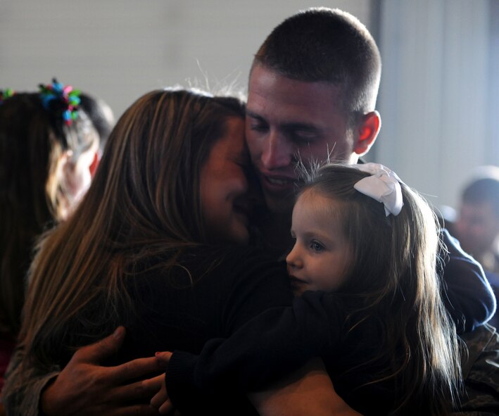 MINOT AIR FORCE BASE, N.D. – Senior Airman Christopher Comer, 5th Aircraft Maintenance Squadron communication navigation systems journeyman, embraces his wife, Taylor Comer, and daughter after returning home here on April 4 from a six month deployment to Andersen AFB, Guam. Minot’s 69th Bomb Squadron and 5th Bomb Wing personnel deployed to Andersen AFB last November in support of U.S. Pacific Command’s Continuous Bomber Presence. This was the 69th BS’ first deployment since it’s reactivation in September 2009 and the first major combat deployment of aircraft and personnel since World War II. (U.S. Air Force photo/Airman 1st Class Jose L. Hernandez)