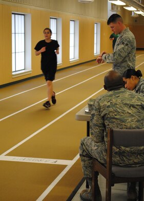 Airman 1st Class Cory Summers times CAP Cadet Airman 1st Class Lauren Daniel during her 1-mile run on the indoor track at the Fitness Center March 26. (U.S. Air Force photo/Airman Cortney Hansen)
