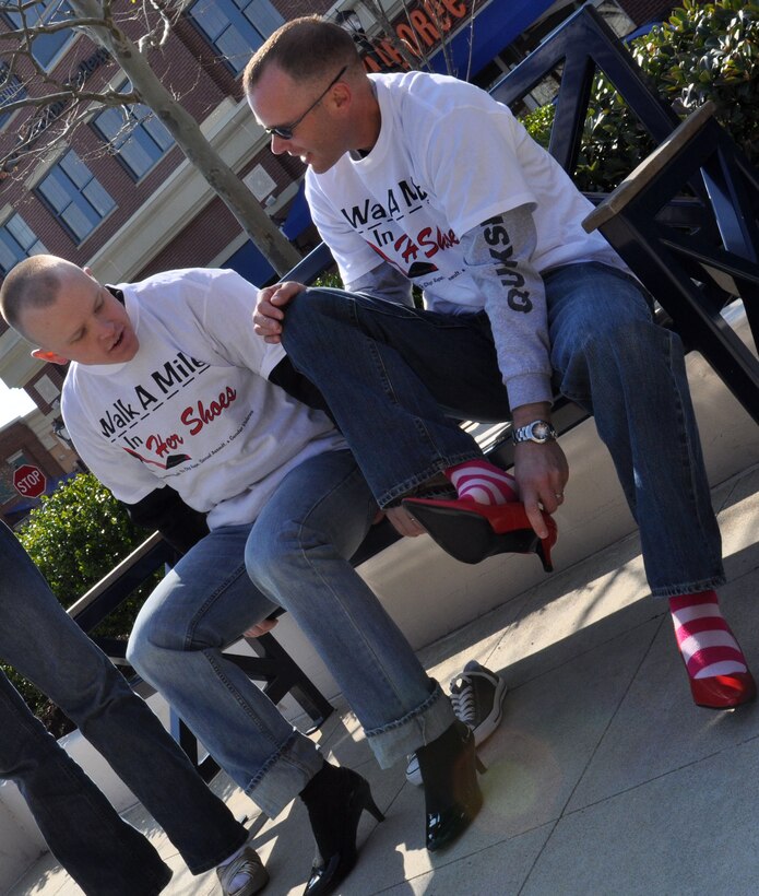 Staff Sgt. Garrett Eckert, 633d Communications Squadron network integration craftsman, watches as Tech. Sgt. Greg Styer, 633d CS network integration noncommissioned officer in charge, puts on his shoes before participating in Walk a Mile in Her Shoes in Hampton, Va., April 2, 2011. The annual march is a “fun way for men to show their support in the fight to end sexual violence” during Sexual Assault Awareness month. (U.S. Air Force Photo/Tech. Sgt. Christina M. Styer/RELEASED)  