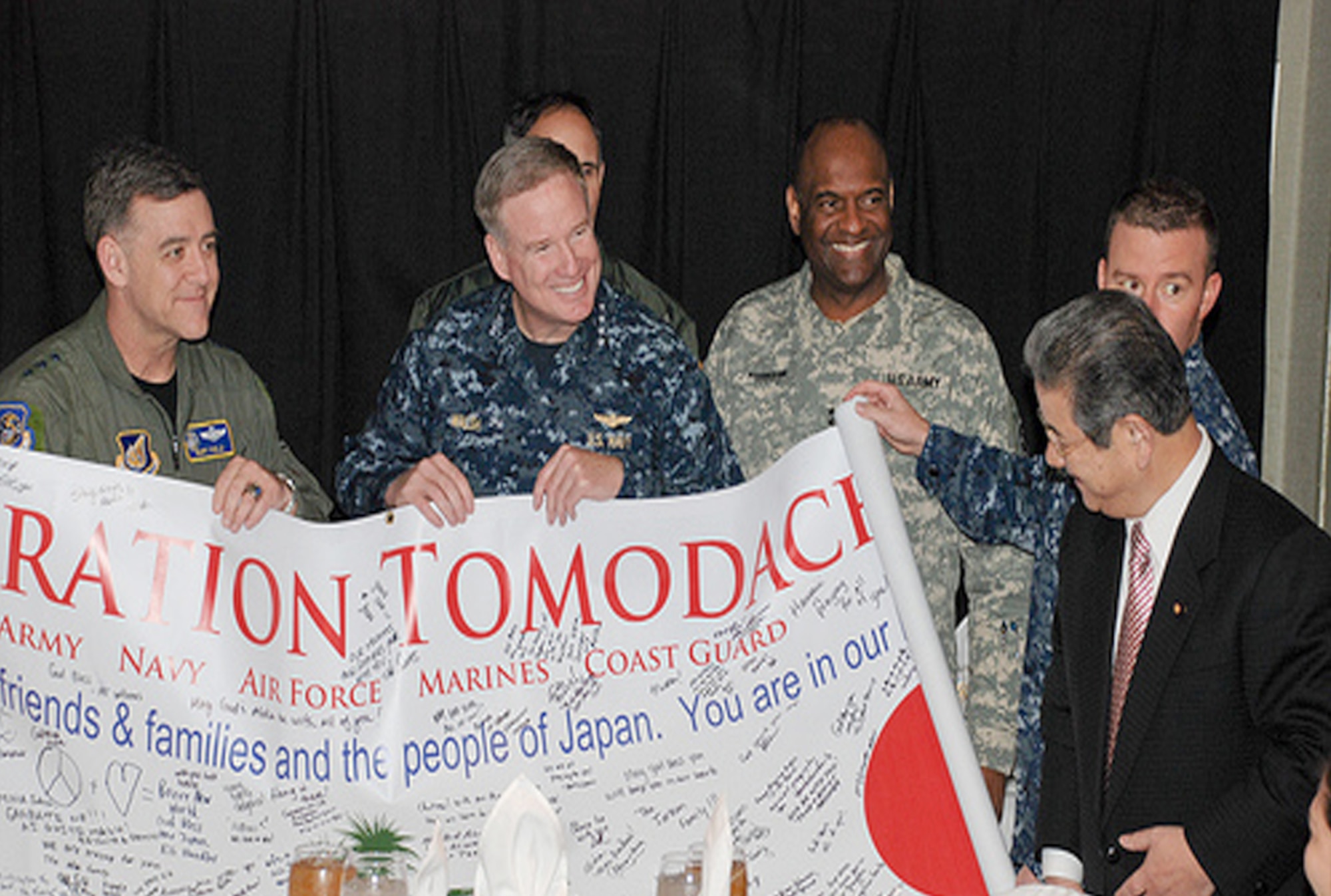 Japanese Defense Minister Toshimi Kitazawa views a banner created by U.S. service members in honor of Operation Tomodachi during his visit to the USS Ronald Reagan, April 4, 2011. Holding the banner are Commander, U.S. Forces Japan, and Commander, 5th Air Force, Pacific Air Forces Lt. Gen. Burton Field; and U.S. Pacific Fleet Commander Navy Adm. Patrick Walsh. (U.S. Navy photo/Petty Officer 3rd Class Kyle Carlstrom)