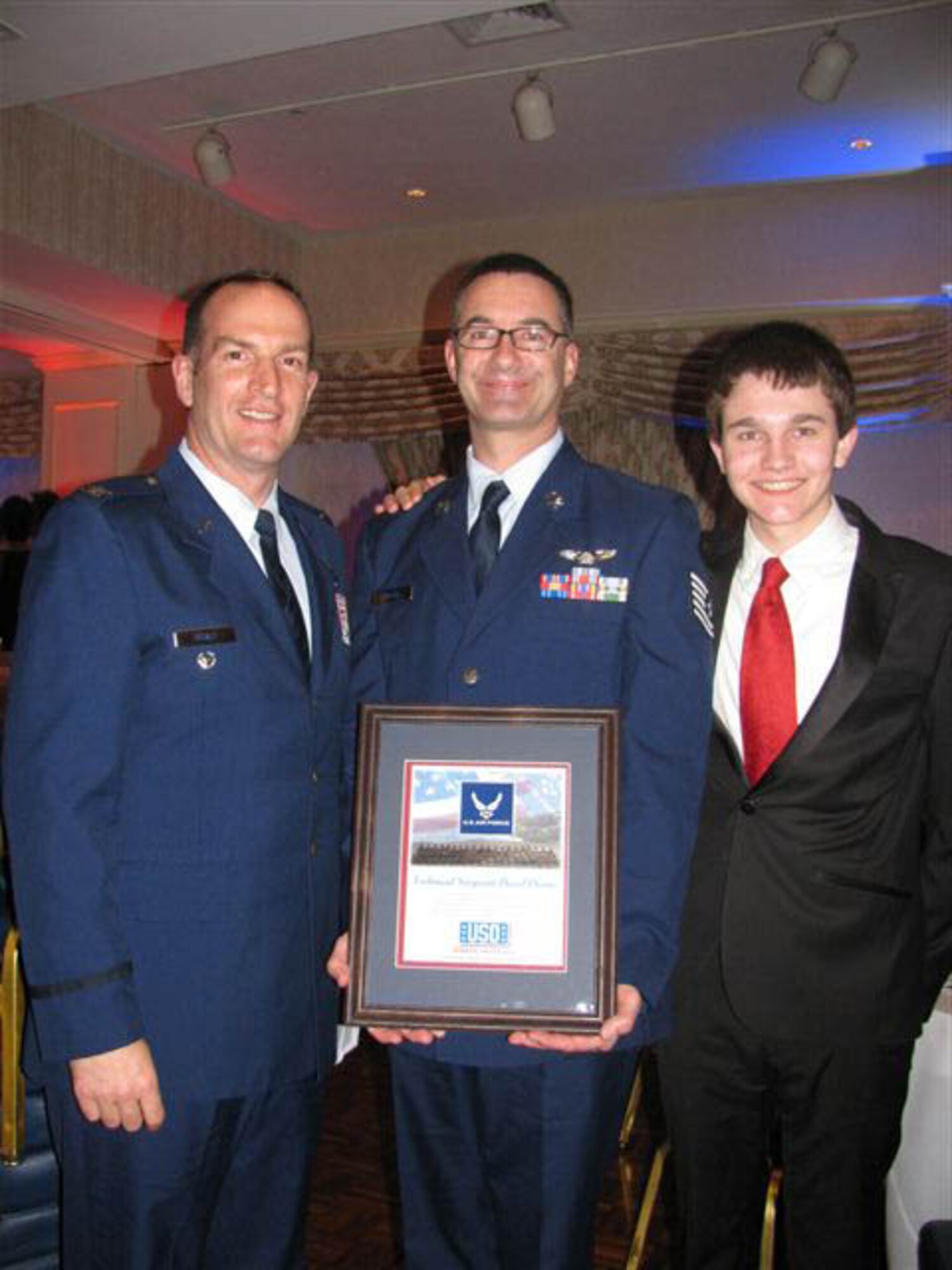 Col. John Healy, 439th Airlift Wing vice commander, congratulates Tech. Sgt. David Owens, 337th Airlift Squadron, who was honored April 2 at a Pioneer Valley USO event held in Holyoke, Mass. Sergeant Owens, joined by his son pictured here, was honored as the 22nd Air Force NCO of the Year. He will soon compete at the command-level awards. (US Air Force photo/Chief Master Sgt. Kathy Wood)