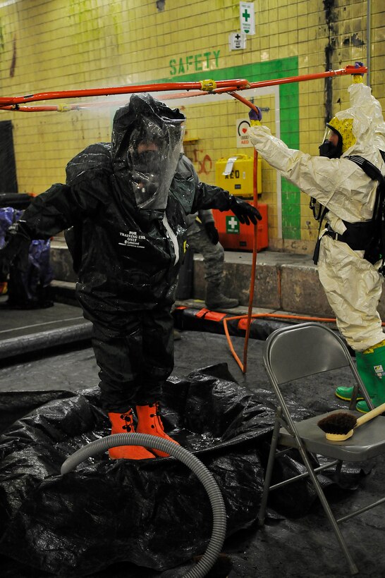Members of the 79th Medical Wing and 11th Civil Engineer Squadron perform a "wet decontamination" upon returning from a simulated radioactive site as part of annual Black Flag training at the Center for National Response in Gallagher, W. Va, March 29. Prior to removing a hazardous material suite, all personnel that may have been exposed must decontaminate themselves in order to not spread radiation. (U.S. Air Force photo by Senior Airman Melissa V. Brownstein)