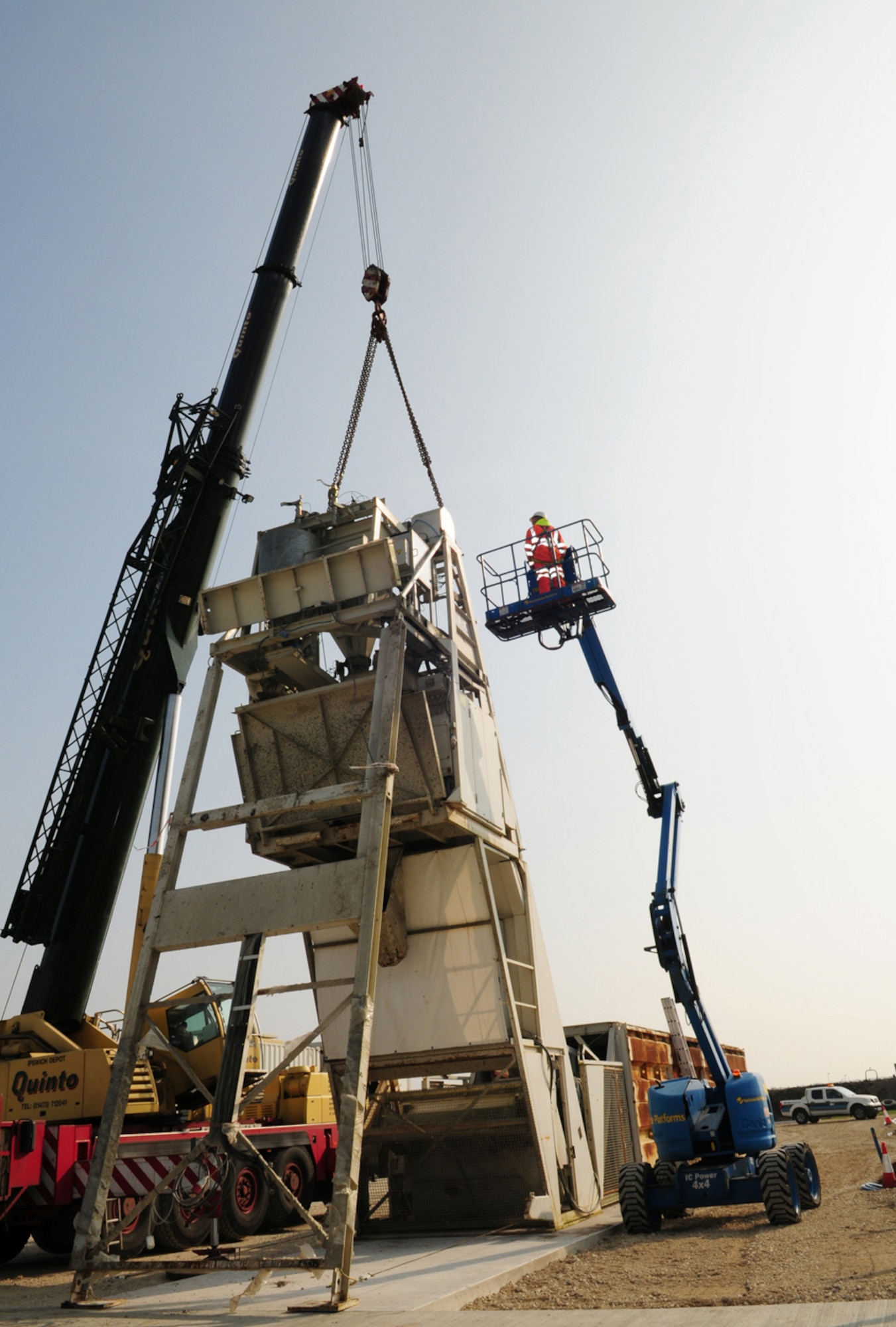RAF MILDENHALL, England -- A contractor uses a lift to inspect the A-frame mixer plant at the concrete batching site here March 29, 2011. Once up and running, concrete will be mixed and discharged into a chute, before being transferred to a mixer truck. The ingredients to make the concrete come out of the aggregate bins near the bottom of the A-frame, get transferred onto a weigh belt before going onto a conveyer belt and into a skip. The mixture then travels upwards before going into a mixing panel. Two cubic meters of the mixture are produced per batch, which is equivalent to more than 2.6 tons. (U.S. Air Force photo/Karen Abeyasekere)