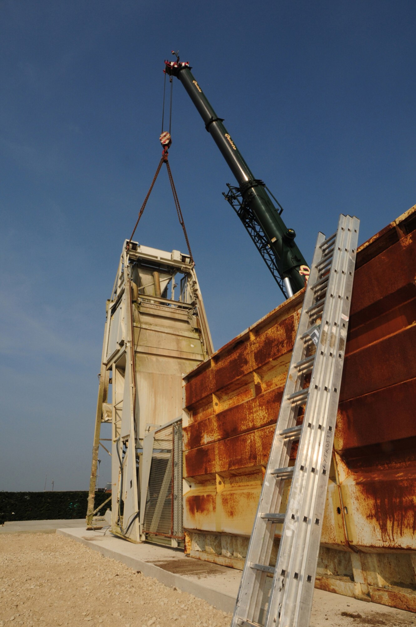 RAF MILDENHALL, England -- An A-frame mixer plant is put into place using a crane March 29, 2011, at the temporary concrete batching plant here. By mixing concrete on base, the number of trucks necessary to complete the airfield repairs being carried out during the next six months will be halved. Congestion at the main gate will also be reduced, which is a significant factor in reducing the impact on the local community. (U.S. Air Force photo/Karen Abeyasekere)