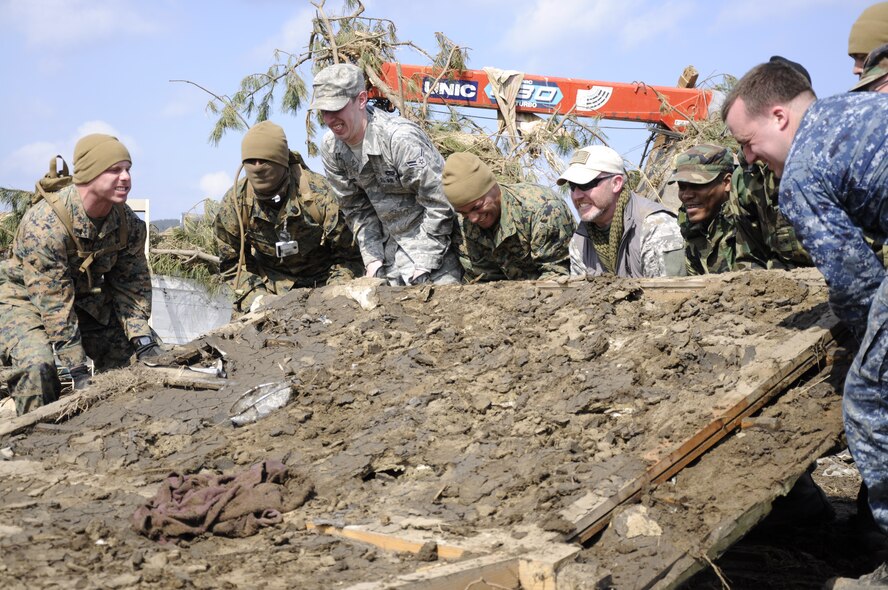 NODA MURA, Iwate, Japan – U.S. service members and civilians lift a knocked-down wall in a tsunami-struck area here March 29. Nearly 40 U.S. service members and civilians left Misawa Air Base, Japan, to assist in tsunami cleanup and relief efforts in the village as part of Operation Tomodachi. (U.S. Air Force photo by Senior Airman Joe McFadden/Released)