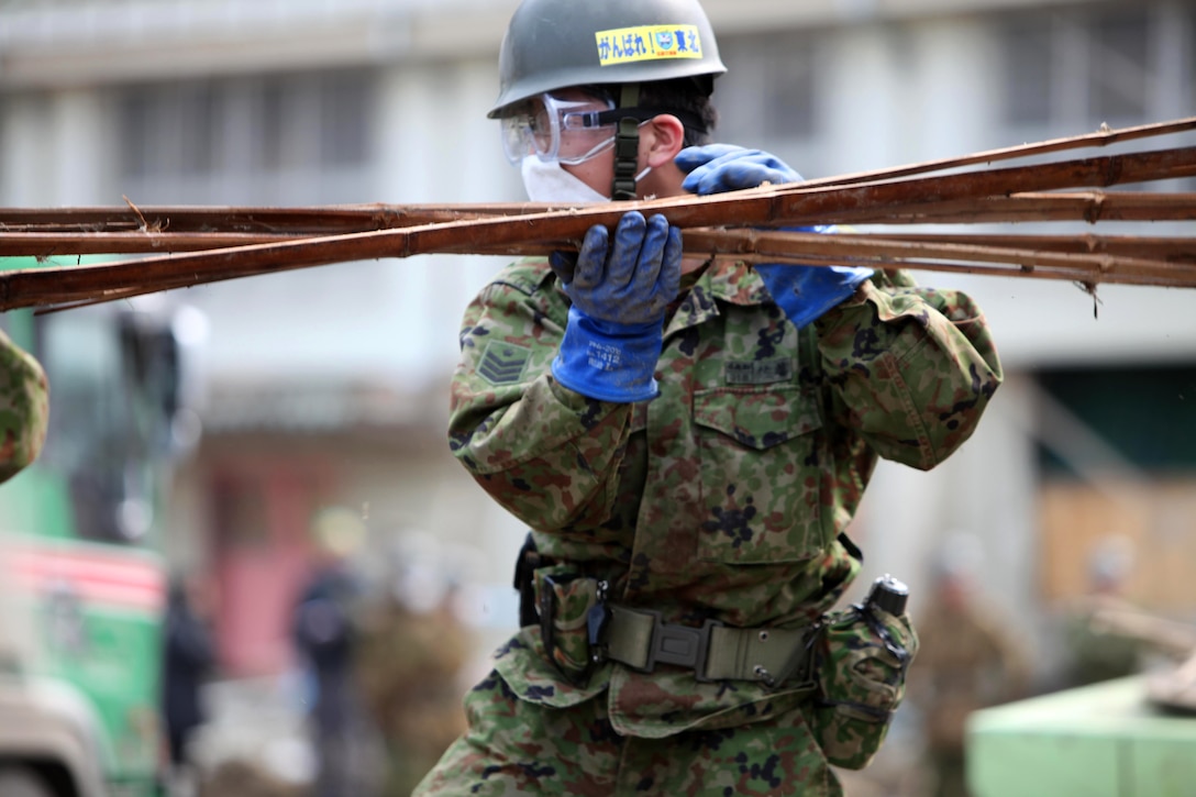 A member of the Japan Self-Defense Force collects debris at the Minato Elementary School in Ishinomaki, Aichi, Japan. April 2, 2011.