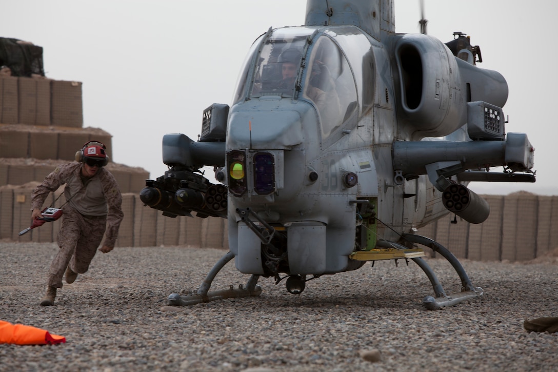 Lance Cpl. Brent Nodland, an aviation ordnance technician with Marine Light Attack Helicopter Squadron 169, maneuvers around a AH-1 Cobra to arm its weapon system prior to take-off at a new forward arming and refueling point at Combat Outpost Ouellette in Afghanistan's Helmand province, April 5.The forward arming and refueling point was recently constructed at Combat Outpost Ouellette to enable 2nd Marine Aircraft Wing (Forward) to better support Marines and other coalition troops operating near Sangin, Afghanistan.