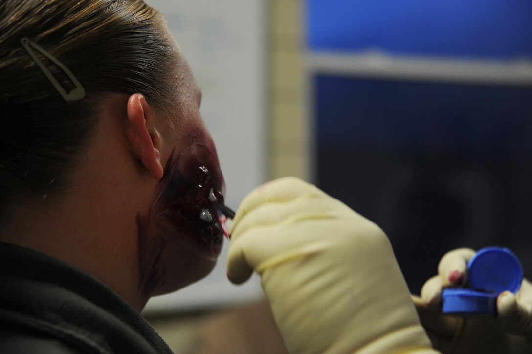 A medic applies simulated injuries to Staff Sgt. Jesse Ford, 779th Aerospace medicine squadron bioenvironmental engineer craftsman,  during a Black Flag exercise at the Center for Center for National Response in Gallagher W.Va, March 31. Sergeant Ford acted as a victim during a mock mass causality disaster at the commissary.  (U.S. Air Force photo by Senior Airman Melissa V. Brownstein)