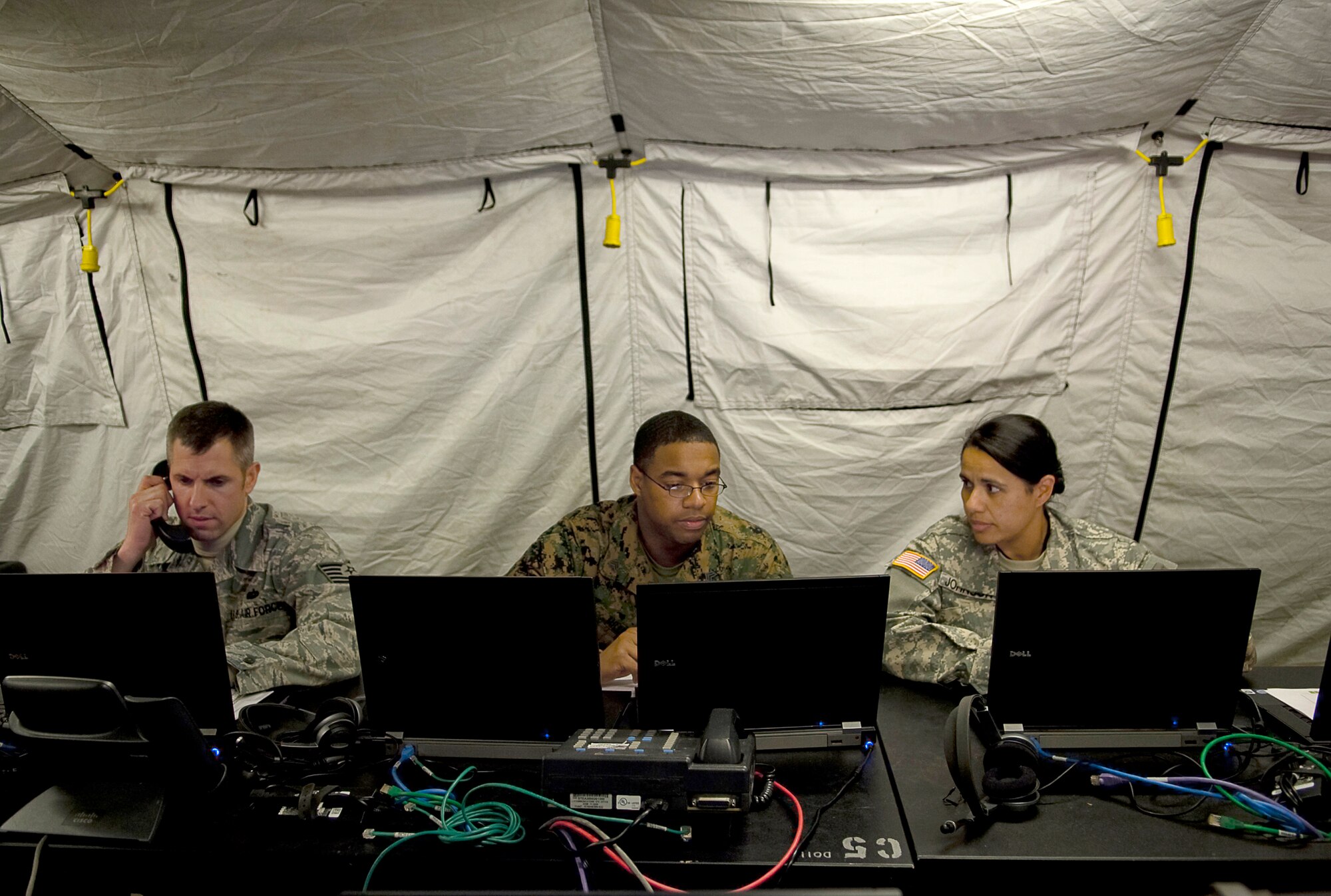 (From left) Tech. Sgt Davis Way, Marine Sgt. Terrall Miller, and Army Spc. Sonya Johnson work on the communicators equipment April 1, 2011, in the Deployable Joint Command and Control System at Yokota Air Base, Japan. The DJC2 is deployed to Yokota AB to provide communications in support of Operation Tomodachi. All service members are assigned to the Joint Communication Support Element. (U.S. Air Force photo/Master Sgt. Jeromy K. Cross) 