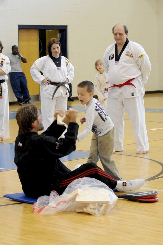 Brad Tinnon, Action Arts Academy tae kwon do instructor, teaches Killian Smith, son of Army Spc. Daniel Smith, 419th Transportation Battalion, how to break a board with his fist during the Family Fun Day event inside the Shellbank Fitness Center at Langley Air Force Base, Va., April 2, 2011. The event was held to promote fitness within the military community and strengthen families while having fun. (U.S. Air Force photo by Staff Sgt. Ashley Hawkins/Released)