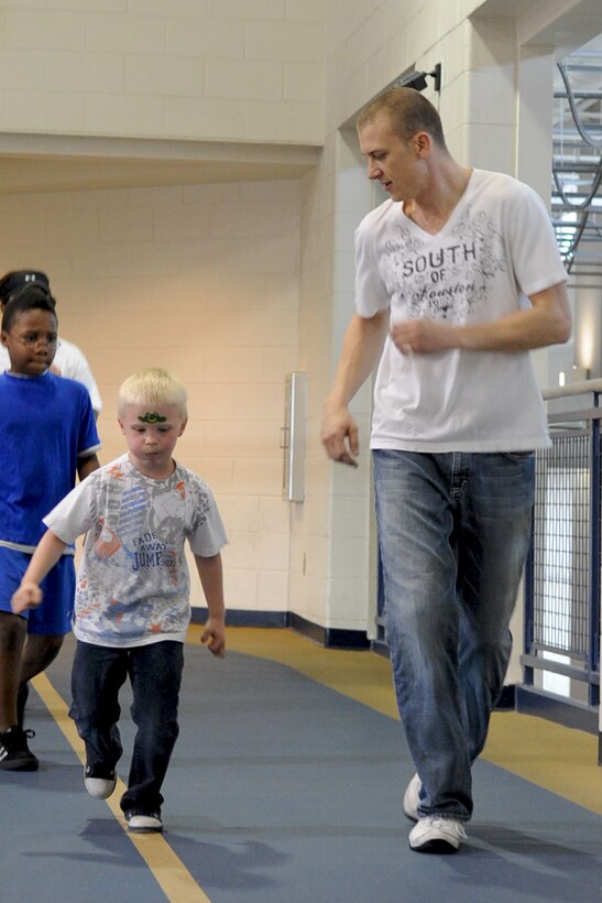 Airman 1st Class Francis Hooker, 94th Aircraft Maintenance Unit crew chief, runs with his four-year-old son, Rysen, during the 1-mile walk/run portion of the Family Fun Day event inside the Shellbank Fitness Center at Langley Air Force Base, Va., April 2, 2011. The event was held to promote healthy living within the military community and to start off the Month of the Military Child. (U.S. Air Force photo by Staff Sgt. Ashley Hawkins/Released)