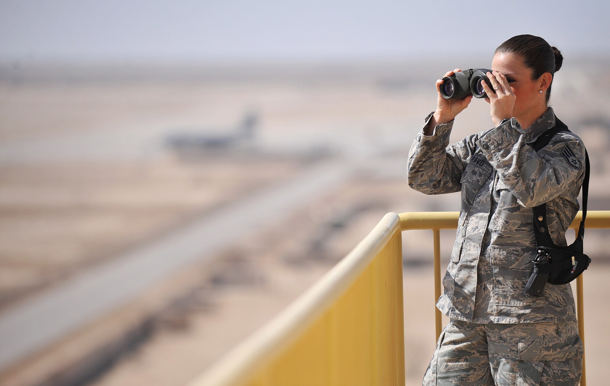 Staff Sgt. Kristen Travo, 407th Expeditionary Operations Support Squadron air traffic controller and Lompoc, Calif., native, takes a look at the flight line through her binoculars from the air traffic control tower March 5, 2011, on Ali Air Base, Iraq. Sergeant Travo is deployed from Hurlbert Field, Fla. (U.S. Air Force photo by Senior Airman Andrew Lee/Released)