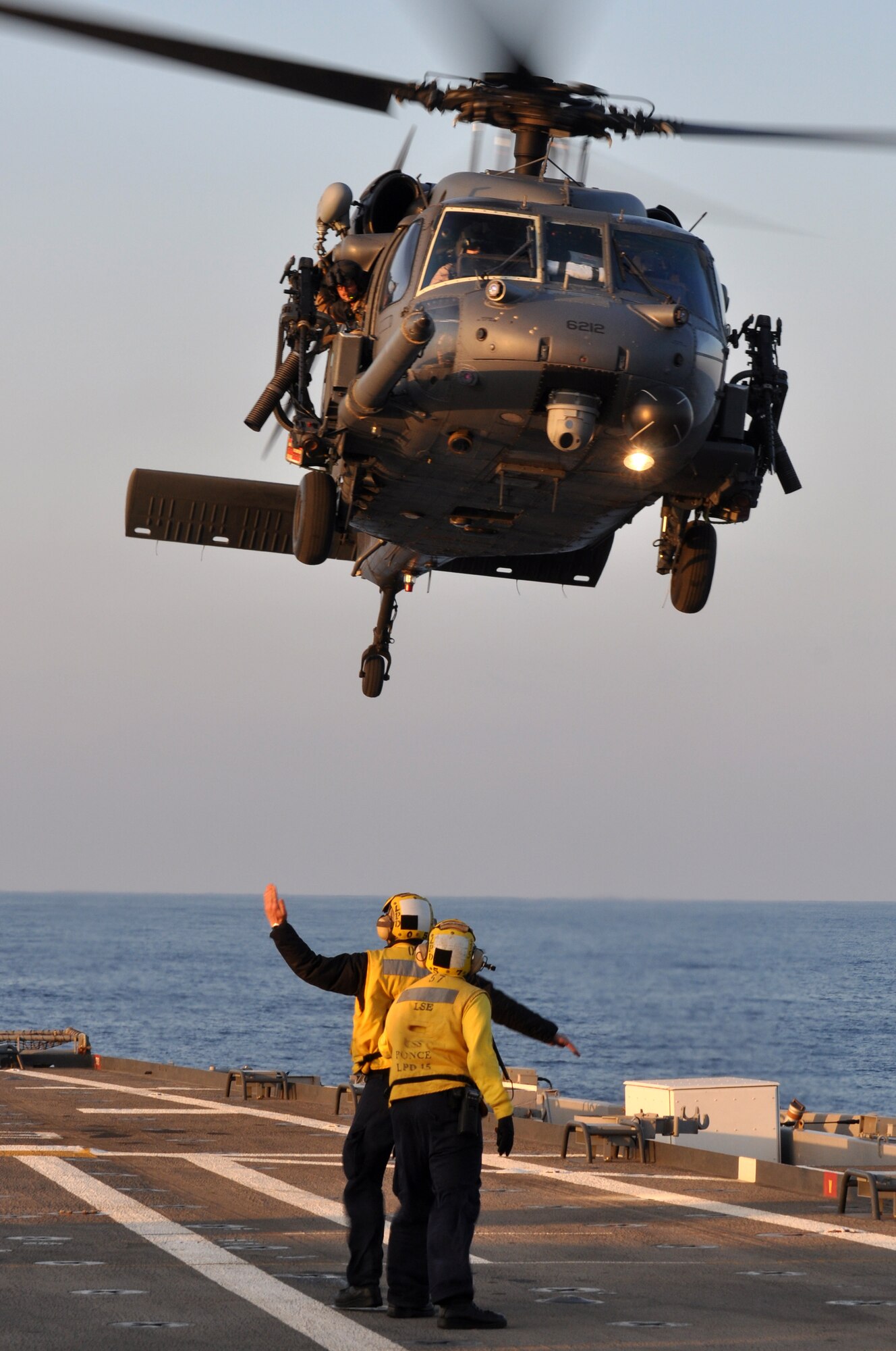 MEDITERRANEAN SEA - Aviation Boatswain’s Mate (Handler) 2nd Class Matthew Kolb supports Aviation Boatswain’s Mate (Handler) Airman John Billington against the powerful down draft of the rotors as Billington directs a U.S. Air Force HH-60G Pave Hawk from the 56th Rescue Squadron while it takes off from amphibious transport dock USS Ponce (LPD 15) during evening training operations on March 25, 2011. Elements of the 56th Rescue Squadron, which is based out of RAF Lakenheath, England, embarked aboard Ponce to provide search and rescue coverage for pilots enforcing the no-fly zone over Libya. Ponce is part of Kearsarge Amphibious Ready Group, supporting maritime security operations and theater security cooperation efforts in the U.S. 6th Fleet area of responsibility. (U.S. Navy photo by Mass Communication Specialist 1st Class Nathanael Miller)