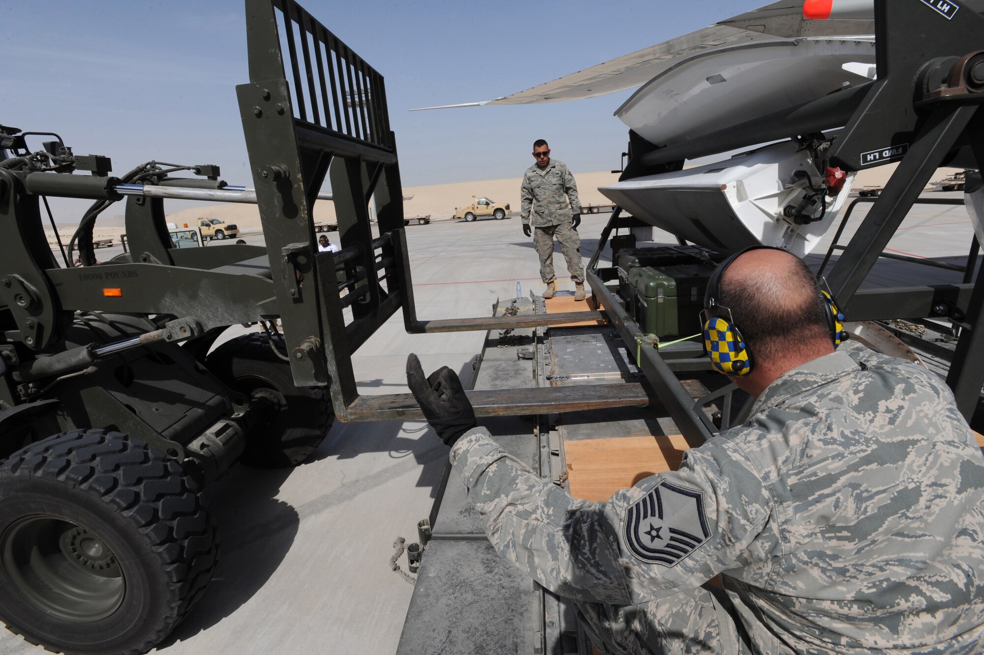Master Sgt. Brian O'Daniel (front), 380th Expeditionary Logistics Readiness Squadron, and Senior Airman Adrian Gonzales, 380th ELRS, help guide the forklift under the cargo equipment Mar. 10, 2011, in Southwest Asia. The Airmen used this opportunity to assist in training the host nation with loading and unloading equipment using heavy machinery. Sergeant O'Daniel and Airman Gonzales are deployed from the 89th Aerial Port Squadron, Andrews AFB, Md. (U.S. Air Force photo by Senior Airman Maynelinne De La Cruz)