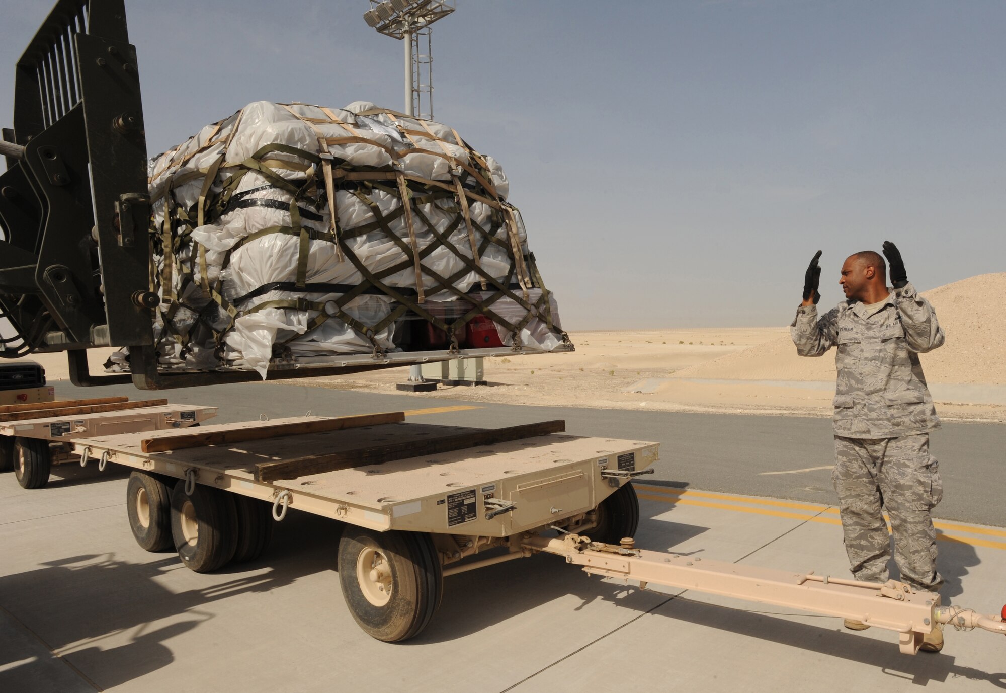 Master Sgt. William Vereen, Host Nation Embassy permanent party, guides the forklift to set cargo down on host nation tow trucks Mar. 10, 2011, in Southwest Asia. The 380th ELRS members assisted their host nation counterparts in unloading their F-16 Desert Falcon equipment used during their first deployment mission to Red Flag. This is the first time for the 380th Expeditionary Logistics Readiness Squadron's Air Terminal Operation Center to assist and train the host nation in training heavy equipment offloading. (U.S. Air Force photo by Senior Airman Maynelinne De La Cruz)