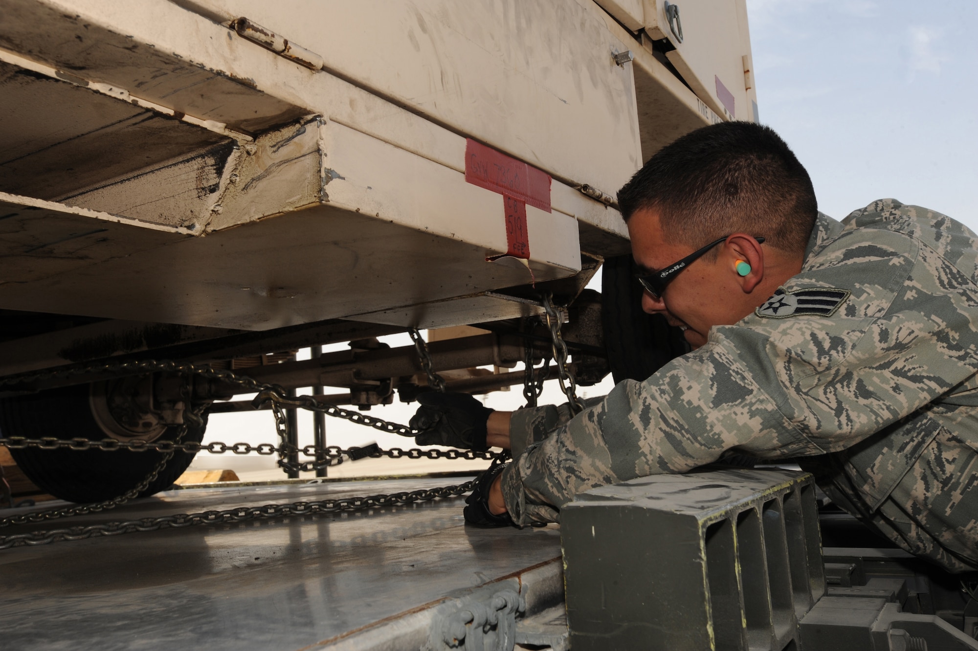 Senior Airman Adrian Gonzales, 380th Expeditionary Logistics Readiness Squadron, unchains some cargo equipment that flew in from the latest Red Flag exercise at Nellis AFB, Nev., on Mar. 10, 2011, in Southwest Asia. The 380th ELRS members assisted their host nation counterparts in unloading their F-16 Desert Falcon equipment used during their first deployment mission to Red Flag. This is the first time for the 380th Expeditionary Logistics Readiness Squadron's Air Terminal Operation Center to assist and train the host nation in training heavy equipment offloading. Airman Gonzales is deployed from the 89th Aerial Port Squadron, Andrews AFB, Md. (U.S. Air Force photo by Senior Airman Maynelinne De La Cruz)
