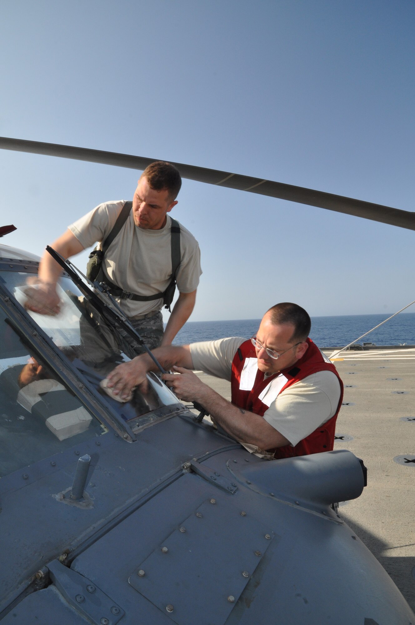 MEDITERRANEAN SEA - U.S. Air Force Tech. Sgts. Eric Myers (left) and Chad Perkins wash the windows on an HH-60G Pave Hawk helicopter from the 56th Rescue Squadron embarked aboard amphibious transport dock USS Ponce (LPD 15) on March 27, 2011. Based out of RAF Lakenheath, England, a detachment from the 56th is aboard Ponce in order to provide combat search and rescue support for coalition forces flying in support of Operation Odyssey Dawn, the coalition effort to bring humanitarian relief to the Libyan people. Due to the saltwater environment at sea, the 56th Airmen have to clean their aircraft far more frequently in order to prevent salt corrosion from damaging vital components. Ponce is part of Kearsarge Amphibious Ready Group, supporting maritime security operations and theater security cooperation efforts in the U.S. 6th Fleet area of responsibility. (U.S. Navy photo by Mass Communication Specialist 1st Class Nathanael Miller)
