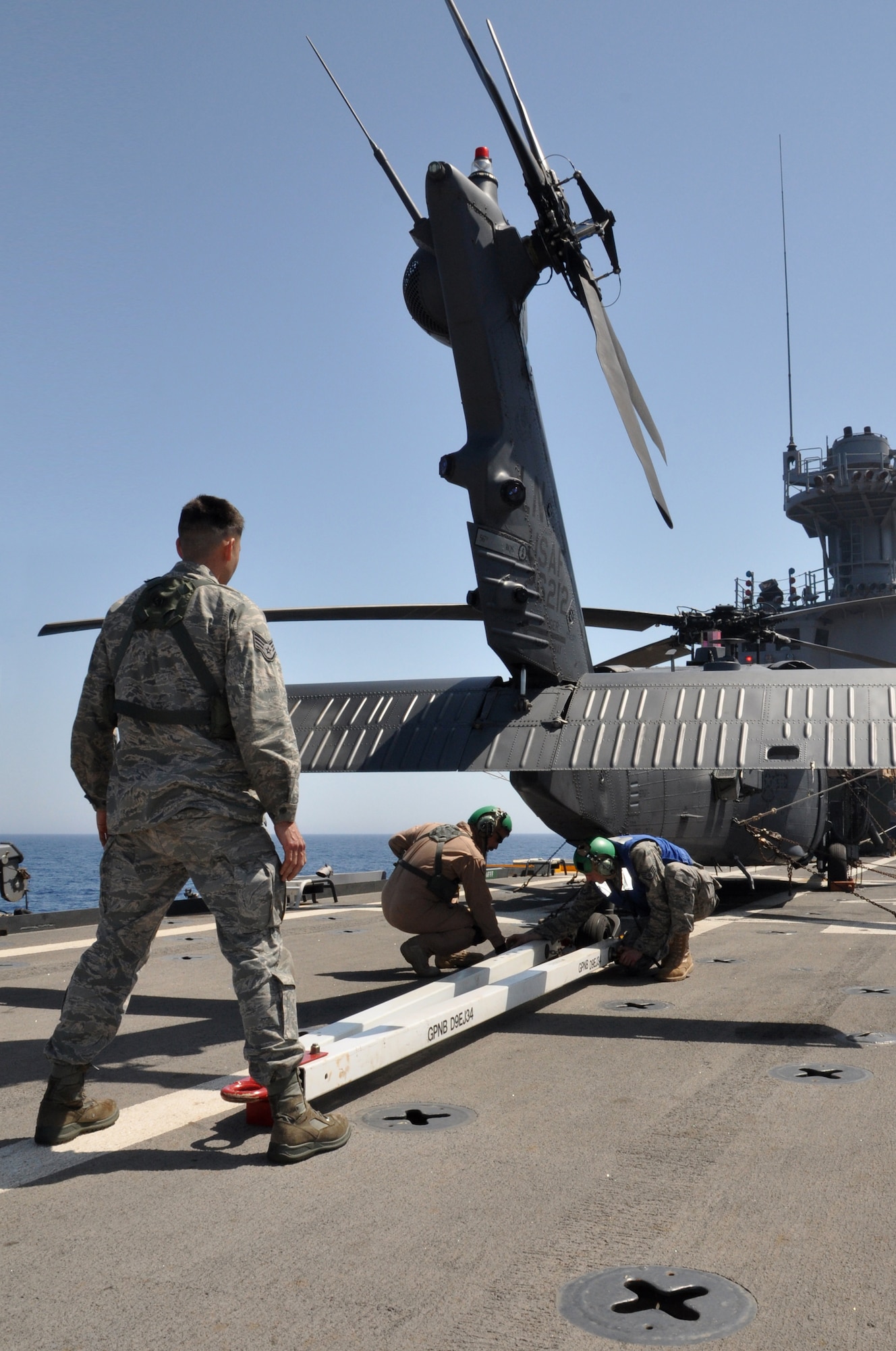 MEDITERRANEAN SEA - U.S. Air Force Staff Sgt. Garrett Fillingham watches as Tech. Sgt. Patrick Ledbetter (left, brown flight suit) and Staff Sgt. Benjamin Halaszynski (right, blue vest) attach a tow bar to an HH-60G Pave Hawk helicopter from the 56th Rescue Squadron embarked aboard amphibious transport dock USS Ponce (LPD 15) on March 27, 2011. Based out of RAF Lakenheath, England, a detachment from the 56th is aboard Ponce in order to provide combat search and rescue support for coalition forces flying in support of Operation Odyssey Dawn, the coalition effort to bring humanitarian relief to the Libyan people. Ponce is part of Kearsarge Amphibious Ready Group, supporting maritime security operations and theater security cooperation efforts in the U.S. 6th Fleet area of responsibility. (U.S. Navy photo by Mass Communication Specialist 1st Class Nathanael Miller)