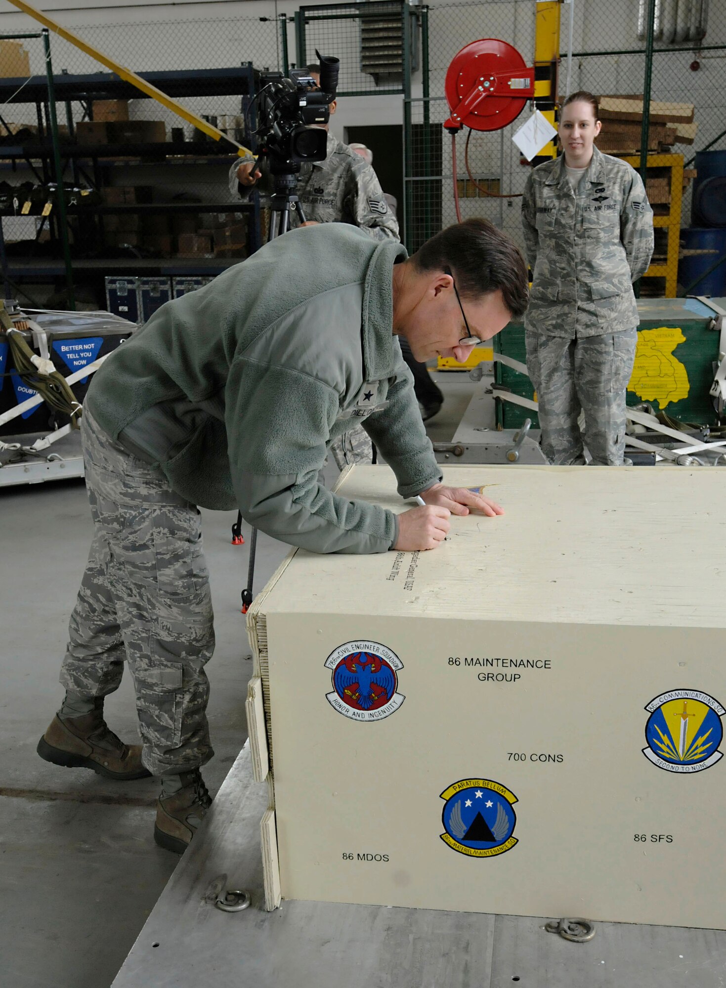 U.S. Air Force Brig. Gen. Mark Dillon, 86th Airlift Wing commander, signs a commemorative heavy training platform designed by Senior Airman Sarah Hathaway, 86th Logistics Readiness Squadron, Ramstein Air Base, Germany, April 4, 2011. The platform will be used to assist in training the 37th Airlift Squadron with heavy equipment airdrops. (U.S. Air Force photo by Airman Kendra Alba) 